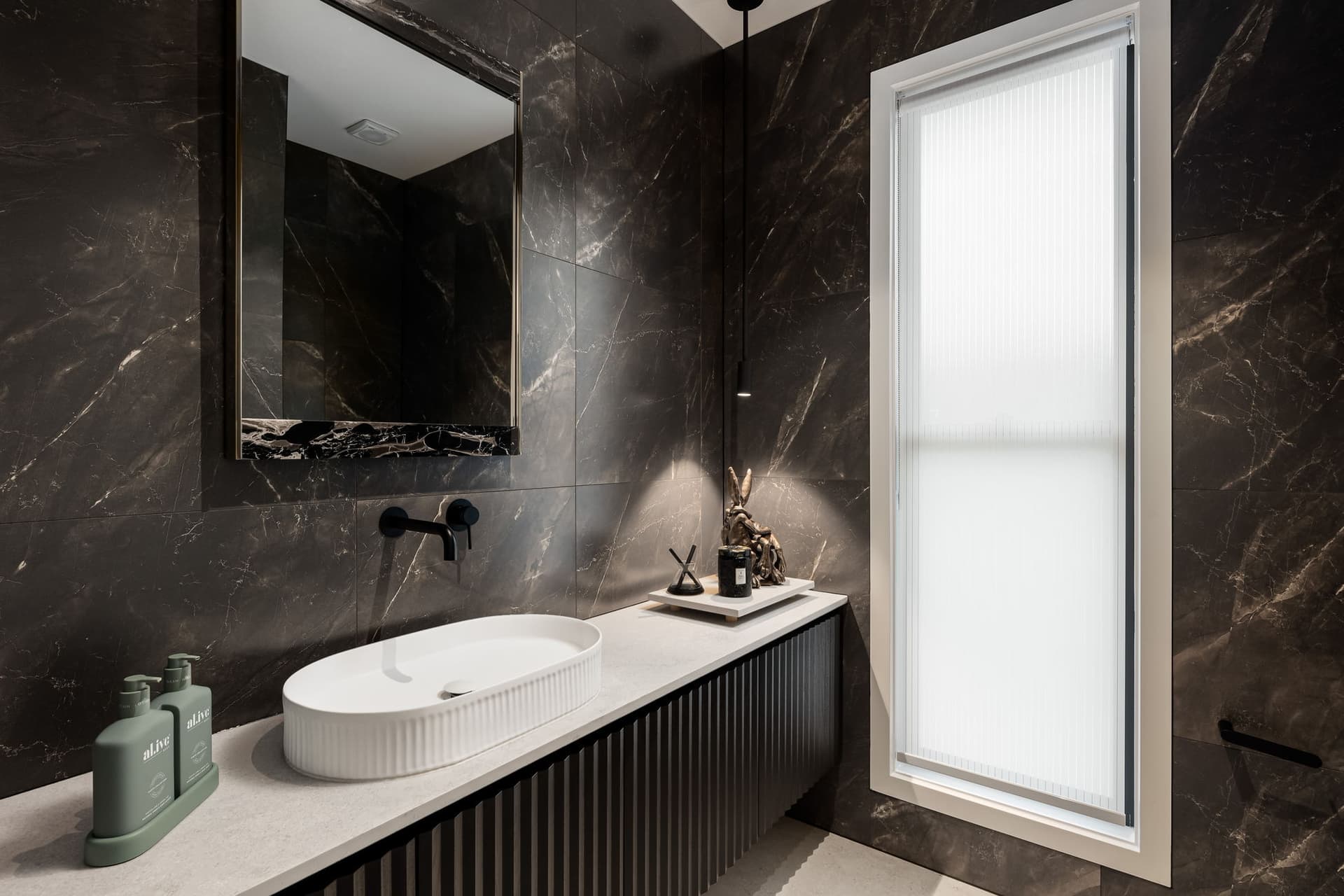 Powder room in dark marble with fluted glass